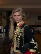 Three-quarter back view of the black military hussar jacket showing the embroidered sleeve motif and red cuff trim