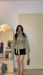 Full-length view of women's belted trench jacket in a light khaki tone, styled with a mini skirt – relaxed front pose