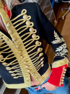 Close-up of gold braided frog closures and embroidered laurel sleeve panel on a black military-style cropped jacket