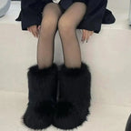Model wearing black fluffy faux fur ankle boots with sheer tights, seated view from the front