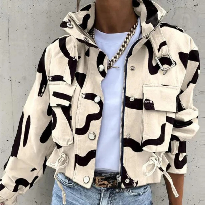 Model wearing a cropped utility jacket in off-white with an all-over black abstract brushstroke print, styled open over a white tee with jeans